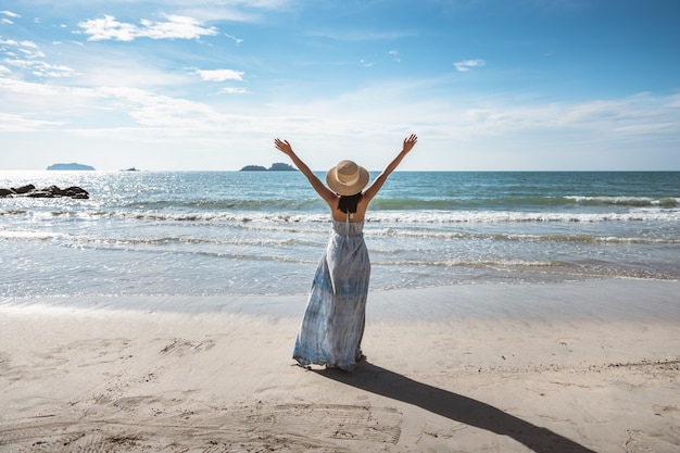 Foto zomer strand reizen vakantie concept, gelukkige reiziger aziatische vrouw met witte jurk ontspannen op het strand in de avond in thailand, vintage stijl