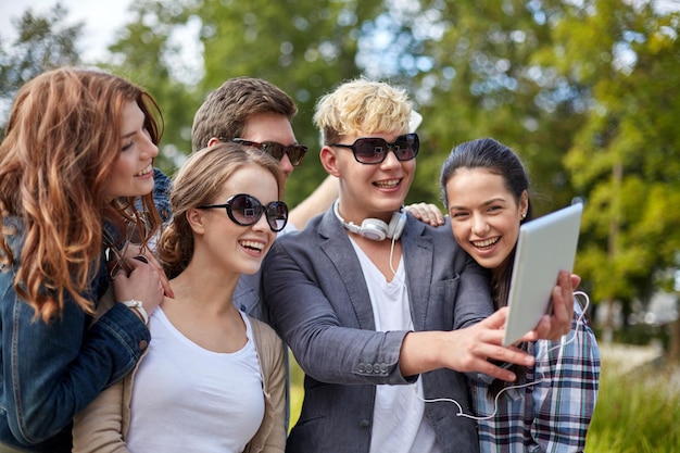 zomer, technologie, onderwijs en tienerconcept - groep gelukkige studenten of tieners met tablet pc-computer die selfie neemt