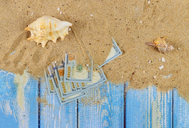 Zomer tijd om te reizen concept zeemosselen in het strand zand over honderd dollar biljetten