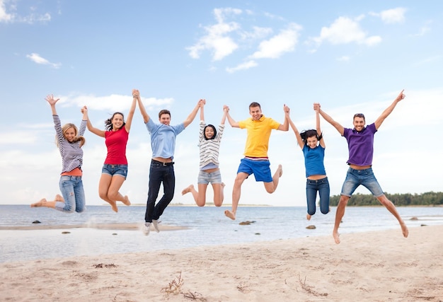 zomer, vakantie, vakantie, gelukkige mensen concept - groep vrienden springen op het strand