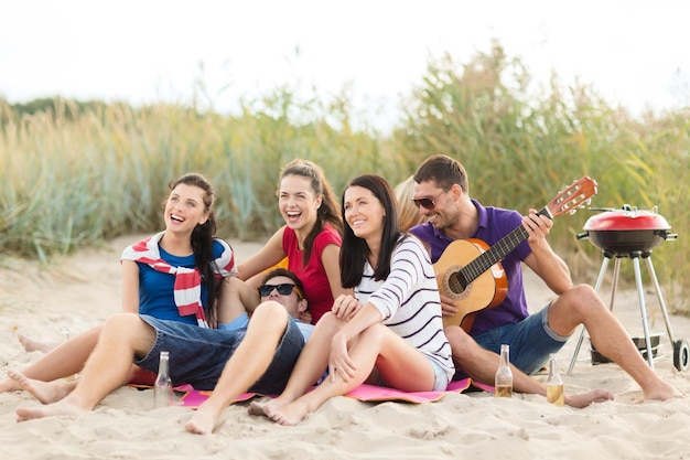 zomer, vakantie, vakantie, muziek, gelukkige mensen concept - groep vrienden met gitaar plezier op het strand