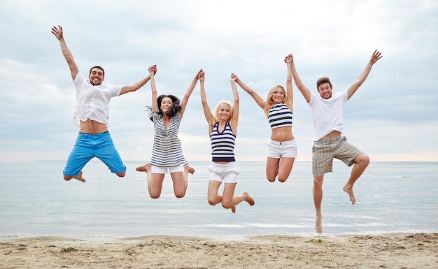 zomer, vakantie, zee, toerisme en mensen concept - groep lachende vrienden in zonnebril wandelen op het strand