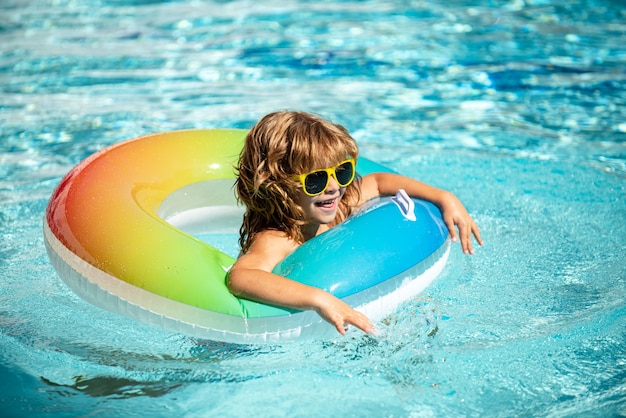 Zomer vakantie. Zomer kinderweekend. Grappige jongen in zwembad op opblaasbare rubberen cirkel in aquapark.