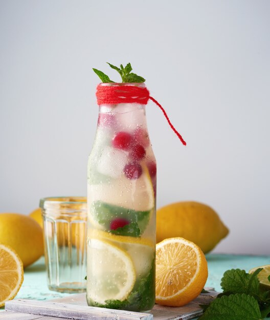 Zomer verfrissend drankje limonade met citroenen, cranberry, muntblaadjes, limoen in een glazen fles