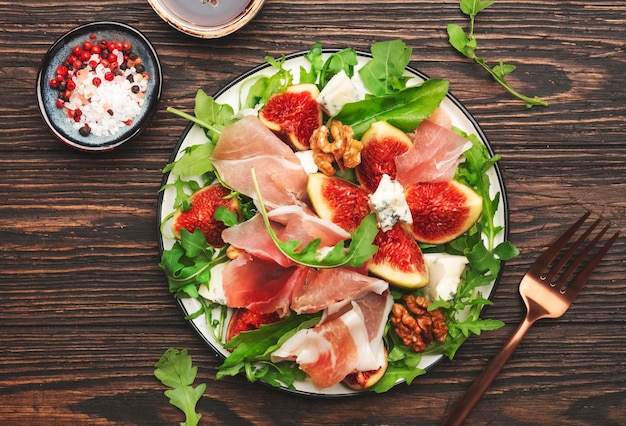 Zomer vijgensalade met jamon blauwe kaas walnoten rucola op oude houten keukentafel achtergrond bovenaanzicht kopie ruimte