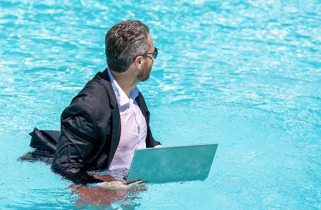 Zomer zakelijke dromen succesvolle man zakenman in pak met laptop in zwembad zakenman op zomervakantie zakenman in nat pak in zwembad op afstand werken kopie ruimte banner