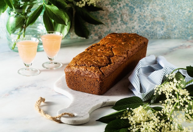 Zomer zoete broodcake op een tafel met bloemen en een drankje in glazen.