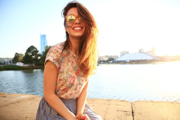 Zomer zonnige levensstijl mode portret van jonge stijlvolle hipster vrouw. Vrouw met witte tanden die in de zomer zijwaarts denkt en kijkt in een park