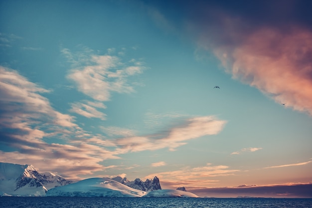 Zomer zonsondergang in Antarctica. Gekleurde zonsondergang wolken boven de oceaan met bergen op de achtergrond. Prachtig winterlandschap