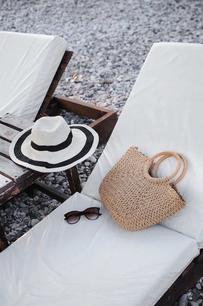 Zomeraccessoires strohoed zomertas en zonnebril op een zonnebank op het strand