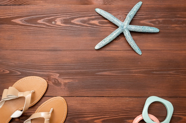 Zomerachtergrond van damessandalen, zeesterren en armbanden op een houten oppervlak