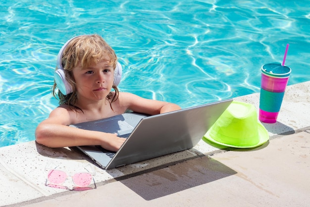 Zomerbedrijf Kind op afstand werkt op laptop in zwembad Kleine zakenman werkt online op laptop in zomerzwembadwater Kleine zakenman werkt aan tropisch strand