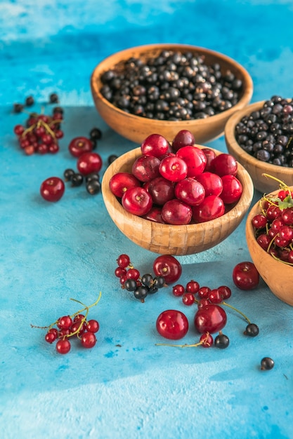 Zomerbessenmix op blauwe betonnen ondergrond bosbessen rode zwarte bessen en kersen