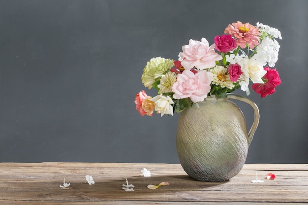 Zomerbloemen in keramische kan op houten tafel