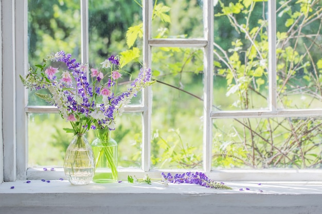 Zomerbloemen in vaas op vensterbank in zonlicht