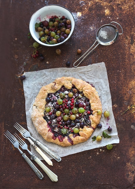 Zomercrostata of galettetaart met verse tuinbessen en vanilleroomijs over grunge roestig metaal, hoogste mening.