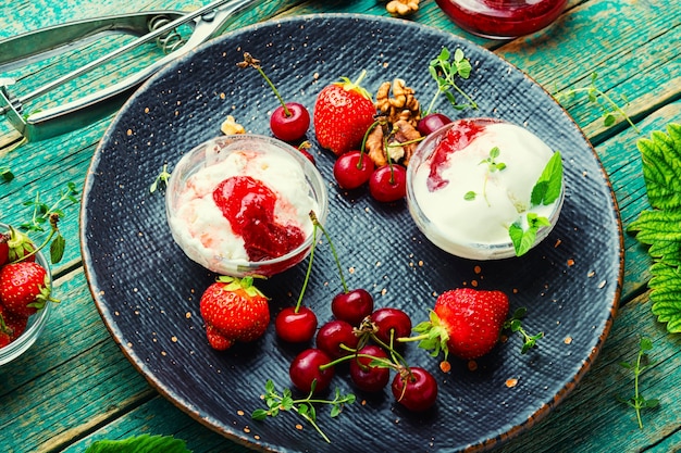 Zomerdessert, ijs met aardbeien en kersen. IJs met bessenjam op houten tafel