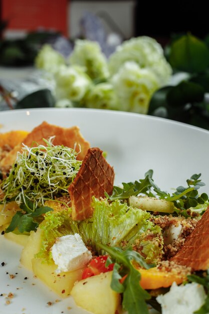 Zomerdieetsalade met bladeren van sla, watermeloen, perzik en fetakaas op een lichtblauwe achtergrond