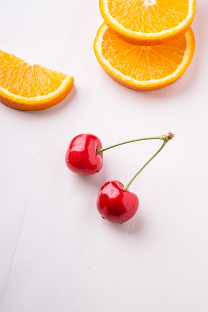 Zomerfruit twee kersen met sinaasappelen op witte hoekmening