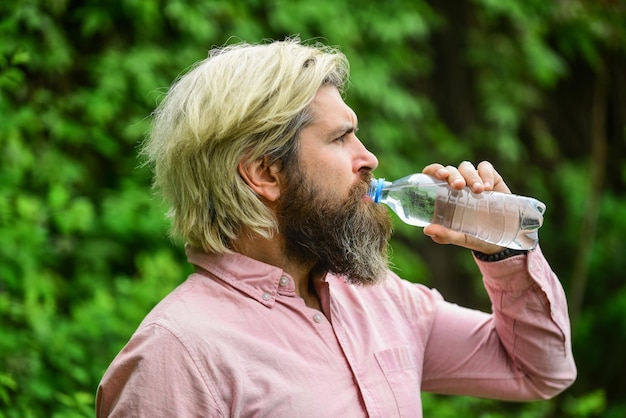 Zomerhitte Drinken van helder water Veiligheid en gezondheid Waterbalans Man bebaarde toeristische drinkwater plastic fles natuur achtergrond Dorstige man drinken gebotteld water Gezonde levensstijl