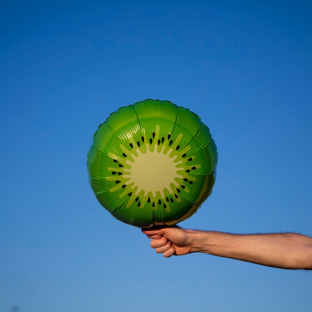 Zomerkiwifruitballon in de lucht gehouden tegen een helderblauwe zomerlucht