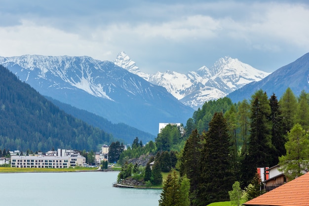 Zomerlandschap met Davos Lake, stadsrand en bergen met sneeuw in de verte (Zwitserland)