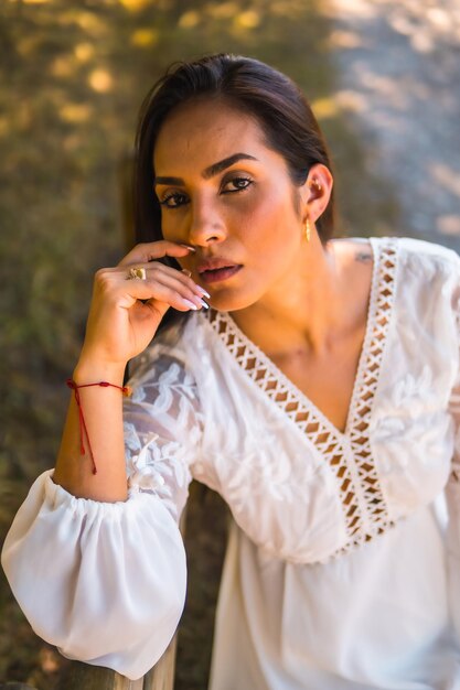 Zomerlevensstijl een jonge Latijnse brunette die geniet van een park in een witte jurk