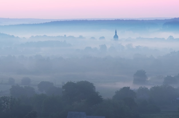 Zomerochtend. Mist in de vallei boven de rivier