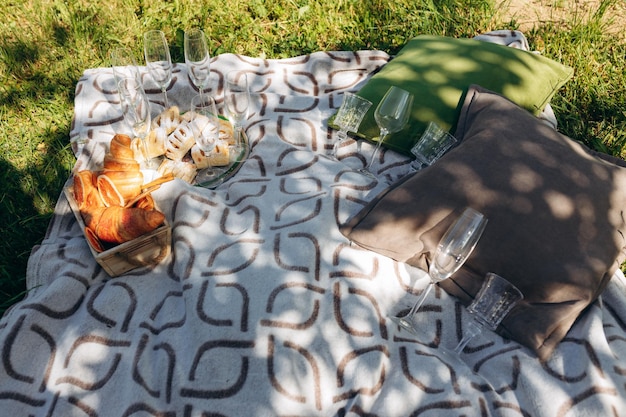 Zomerpicknick buiten op zonnige dag met croissant houten snijplank wijnglas en bruine deken Rustieke, gezellige stijl