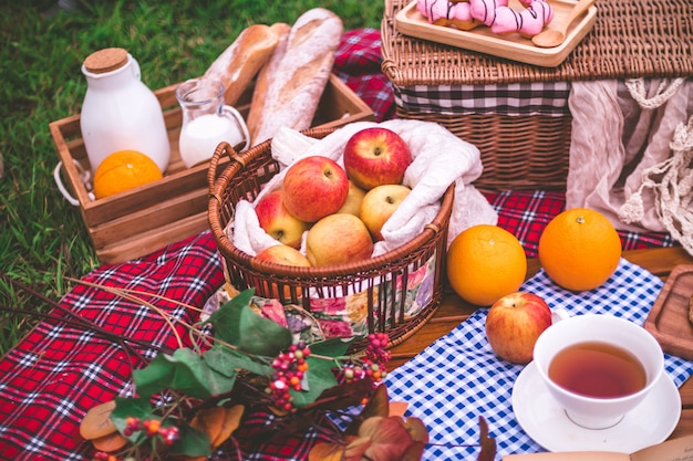 Foto zomerpicknick met een mand met voedsel op deken in het park.