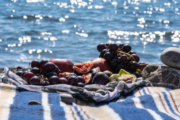 Zomerpicknick met vijgen, druiven en appels. zee en plaid op een strand