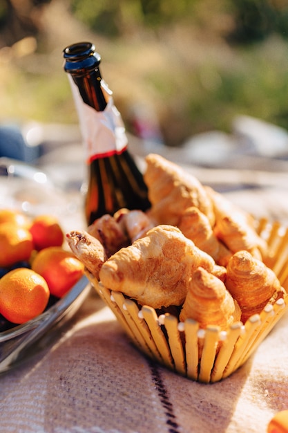 Zomerpicknick op een tapijt met fruit, wijn en thee, kopjes, croissants en zoetigheden