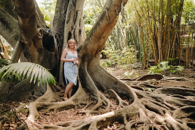 Zomerportret van een gelukkig meisje op het eiland Mauritius dat in de buurt van een enorme boom in de botanische tuin op het eiland Mauritius staat
