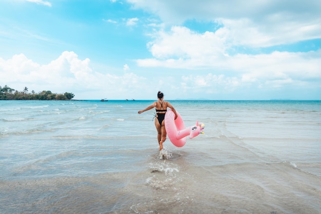 Zomerreisvrouw met een binnenste buis die in het midden van de zee loopt