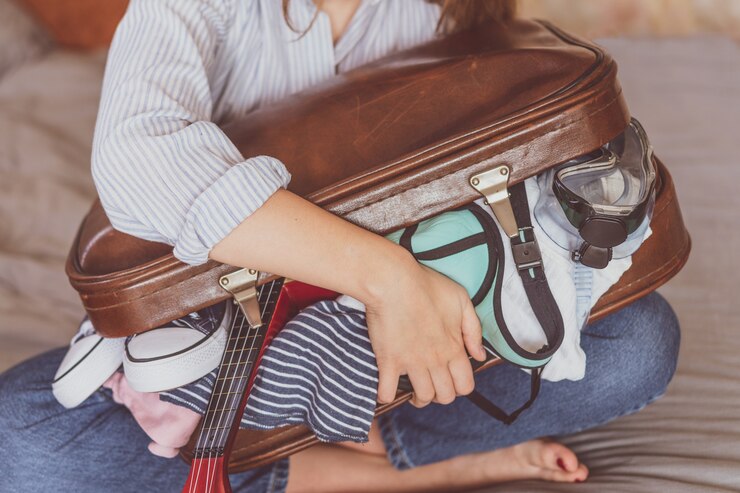 Zomerreizen en vakantie. De jonge koffer van de vrouwenverpakking thuis