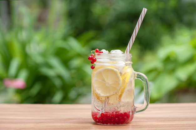 Zomers koel drankje om de dorst te lessen van citroen en bes met ijsblokjes op tafel in de tuin