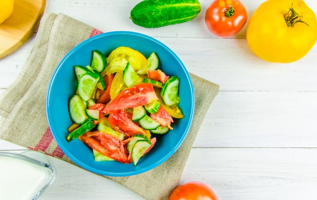 Zomersalade met komkommers en tomaten op witte achtergrond met kopieerruimte