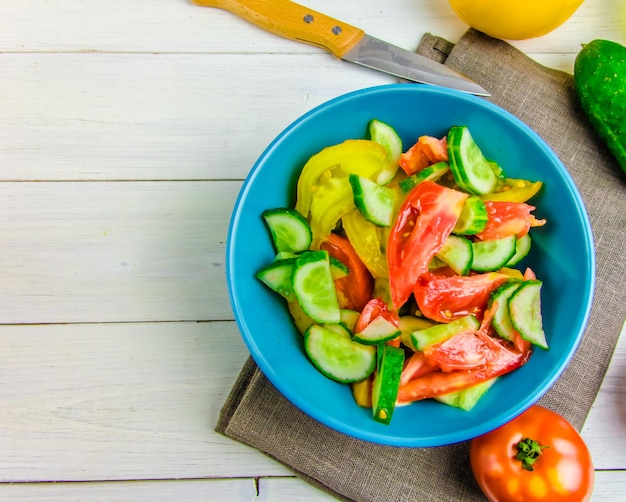 Zomersalade met komkommers en tomaten op witte achtergrond met kopieerruimte