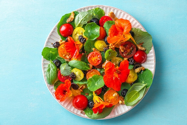 Zomersalade met Oost-Indische kers bloemen groenten en noten op blauwe achtergrond Gezonde voeding voedsel Bovenaanzicht