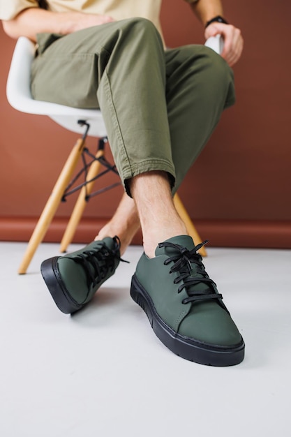 Zomerschoenen Close-up van mannelijke benen in groene broek en groene casual sneakers Zomer lederen herenschoenen