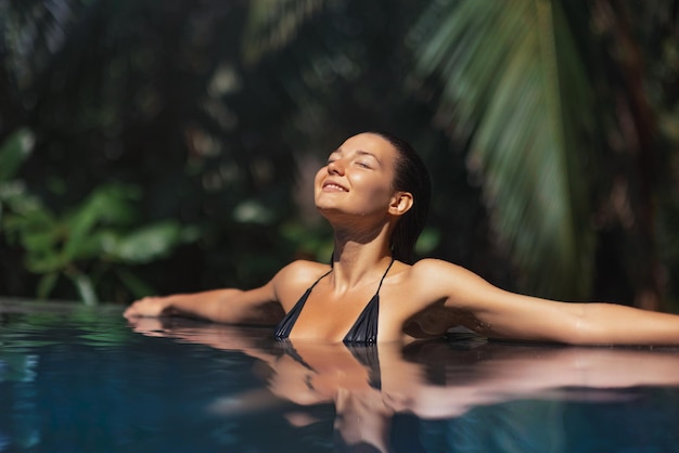 Zomerse gelukzaligheid luxe ontspanning van bikini vrouw in infinity pool