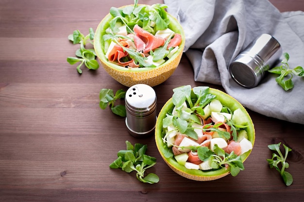 Foto zomerse mediterrane salade met ham en meloen op donker houten tafelblad