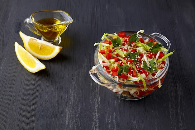 Zomerse salade een licht voorgerecht van witte kool en paprika met peterselie in een glazen kom op een donkere houten tafel