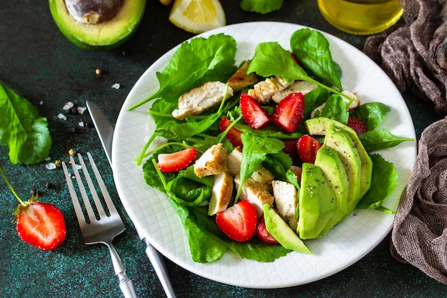 Zomerse salade met aardbeien gegrilde kip en avocado op een stenen tafel