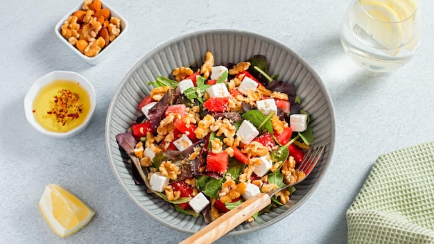 Zomerse verfrissende salade met watermeloen feta kaas, walnoten en groen op betonnen tafelblad met citroenwater bovenaanzicht Recept voor hittegolf