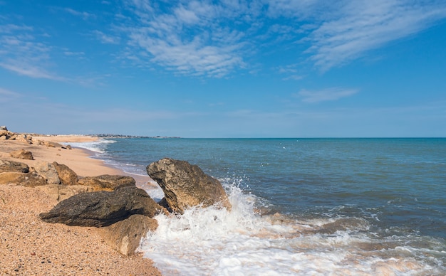 Zomerstrand met rotsen en opspattende golven