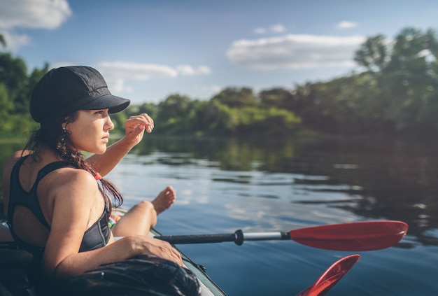 Foto zomervakantie - achteraanzicht van jonge vrouw kajakken op de rivier.