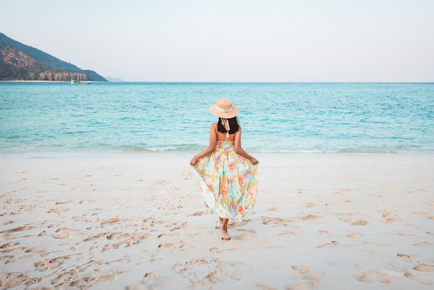 Zomervakantie concept, gelukkige reiziger aziatische vrouw met jurk ontspannen en sightseeing op het strand in de avond op koh lipe, satun, thailand,