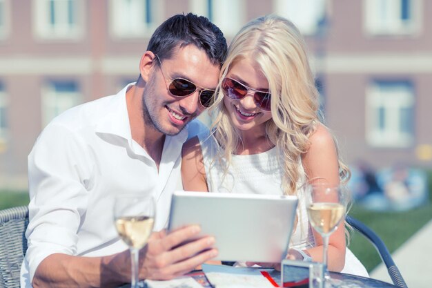 zomervakantie, dating en technologie concept - paar kijken naar tablet pc in café in de stad