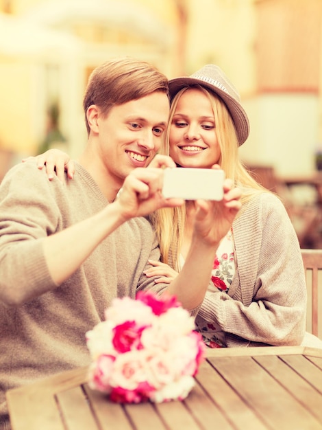 zomervakantie, dating en technologie concept - paar nemen foto met smartphone in café in de stad